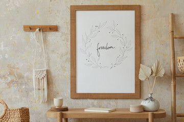Beige boho interior of living room with mock up poster frame, elegant accessories, dried flowers in...