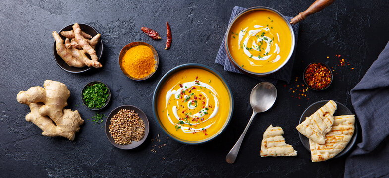 Pumpkin soup with spices in black bowl. Comfort detox food. Flat lay composition. Top view.