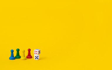 Colorful game chips and two dice are laid out on a yellow background: entertainment, games at home for the whole family, the concept of Board games. Board game. Table games, space for text