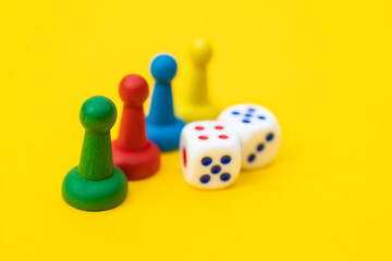 Colorful game chips and two dice are laid out on a yellow background: entertainment, games at home...