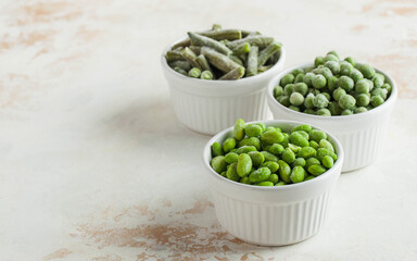 Frozen vegetables green peas, soy, green beans, and baby food in white bowls with copy space. Healthy food, frozen food