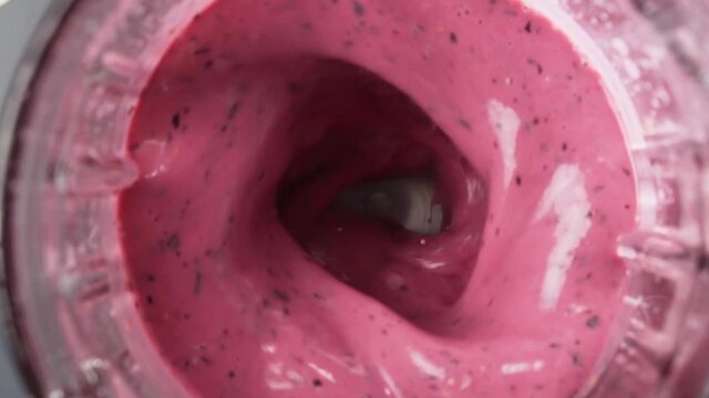Red berry smoothie blended in blender, top view, slow motion.