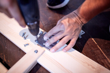 Carpenter hobbyist assembling wooden boards at home / garage.