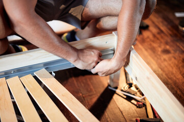 Carpenter hobbyist assembling wooden boards at home / garage.