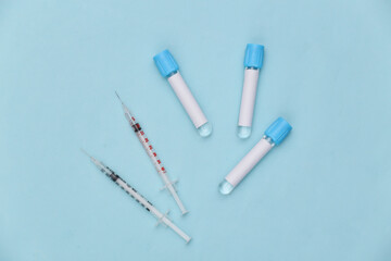 Medical test tubes with syringes on blue background. Vaccination. Top view
