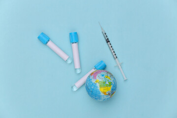 Globe, Medical test tubes with syringe on blue background. Global Vaccination.