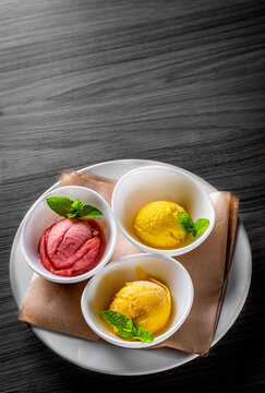 various ice cream desserts with mint leaf on black wooden table