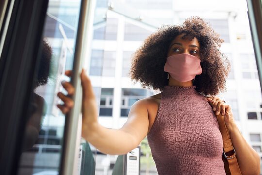 Young adult woman entering office wearing face mask