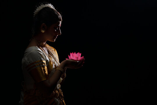Mohiniattam artist smiling at a lotus flower in her hand
