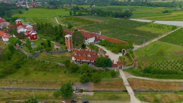 Wide shot of a monastery complex surrounded by fields