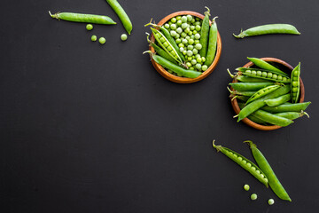 Green pea pods in wooden bowl on the kitchen background