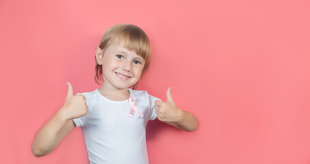 .Little girl showing two thumbs up with pink breast cancer awareness ribbon