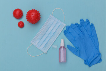 Hygiene. Virus protection. Medical gloves, antiseptic and facial mask on blue background. Top view