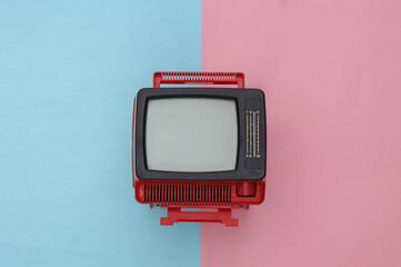 Red retro old mini tv set on pink blue pastel background. Top view