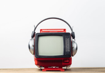 Red retro old portable mini tv set with headphones on white background.