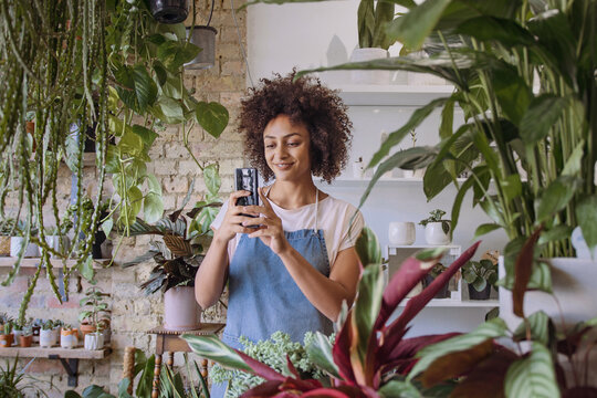 Small business Store Owner using smartphone photographing plants for promotion