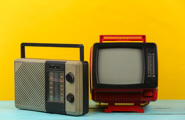 Retro media. Old portable tv, radio receiver on yellow background