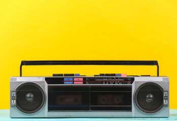 80s Retro outdated portable stereo radio cassette Recorder on yellow background.