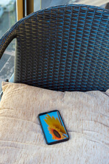Fototapeta na wymiar VIEW OF A MOBILE ON TOP OF A CUSHION ON A CHAIR ON THE BALCONY
