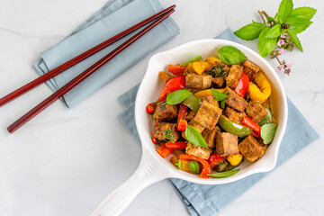 Stir-Fried Tofu and Bell Peppers in a White Skillet Garnished with Thai Basil Leaves,  Directly Above Asian Vegan Food Photography