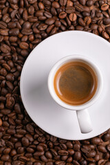 Mugful of coffee in white cup and saucer with coffee grains background