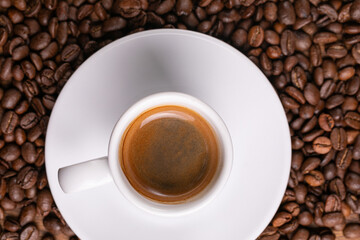 Mugful of coffee in white cup and saucer with coffee grains background