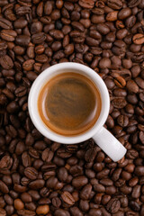 Mugful of coffee in white cup and saucer with coffee grains background