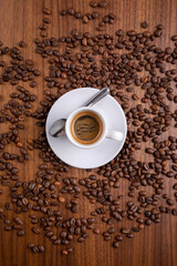 Mugful of coffee in white cup and saucer with coffee grains background