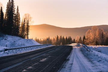 The road in the winter mountains in the background at sunrise
