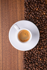 Mugful of coffee in white cup and saucer with coffee grains background
