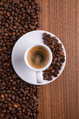 Mugful of coffee in white cup and saucer with coffee grains background