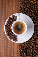 Mugful of coffee in white cup and saucer with coffee grains background