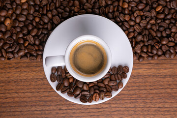 Mugful of coffee in white cup and saucer with coffee grains background