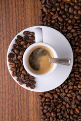 Mugful of coffee in white cup and saucer with coffee grains background