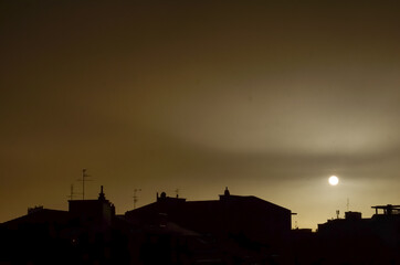 Dark dramatic yellow orange city sunset sky after rain  with building silhouettes with copy space for text. climate change, environment, polution