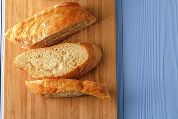 Sliced baguette bread on wooden board close up
