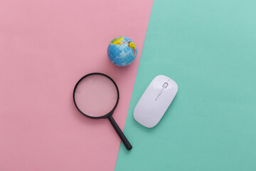 Search information. Pc mouse, magnifier, globe on pink blue pastel background. Top view