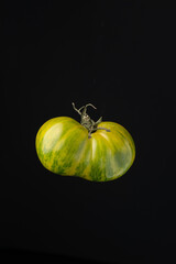 Green tomato on black background