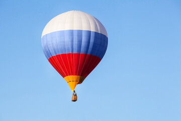 Tricolor hot air balloon flying in the blue sky.
