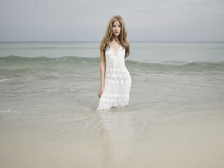 Fototapeta na wymiar Beautiful blonde woman on the beach. Lady in white dress