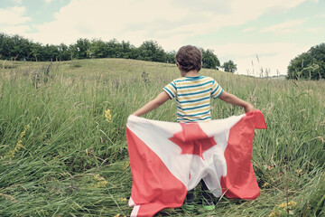 Happy child boy waving the flag of Canada while running