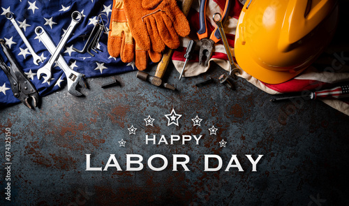 Happy Labor day concept. American flag with different construction tools on dark stone background, with Happy Labor Day text.