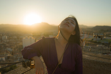 Fototapeta premium young happy and beautiful Asian Korean woman outdoors at viewpoint balcony enjoying sunset view of Spain town during Europe holiday travel feeling free