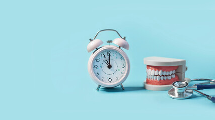 White teeth model with alarm clock and stethoscope on blue background. me to dental health. Dentist day concept. copy space for text.