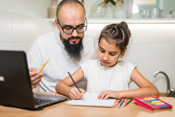 Young father checking homework helping cute school child daughter with studies sit at kitchen table.
