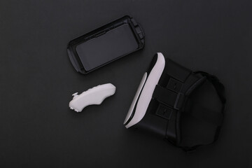 Virtual reality headset with joystick and smartphone on black background. Modern gadgets. Top view
