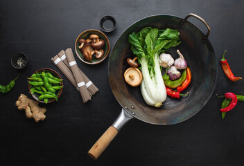 Asian culinary ingredients with wok on a dark surface