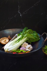 Asian culinary ingredients with a wok on a dark kitchen table surface