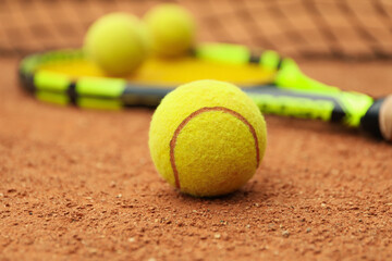 Tennis racquet with tennis balls on clay court