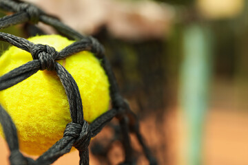 Tennis ball in net, close up and space for text